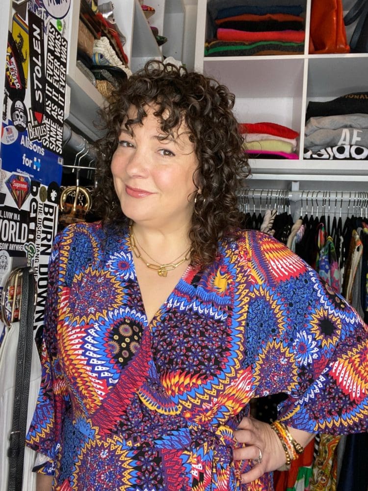 Alison Gary in a colorful printed blouse standing at the entrance to her closet