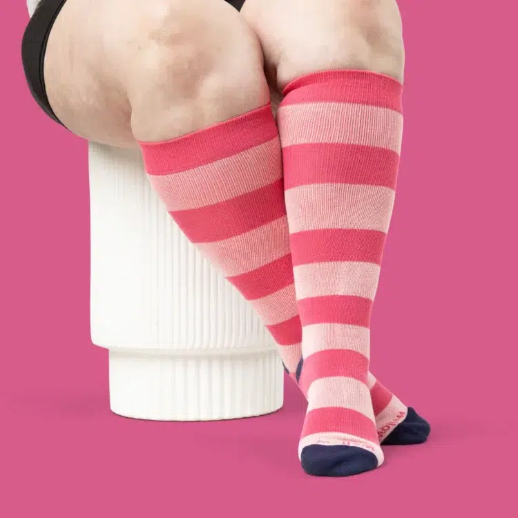 the legs of a model with wide calves wearing pink striped wide calf compression socks from Wellow