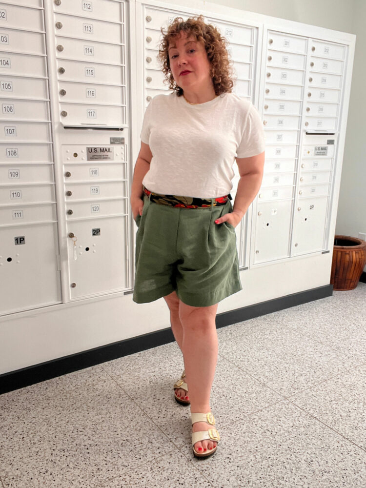 Alison wearing a white t-shirt tucked into loose green linen shorts