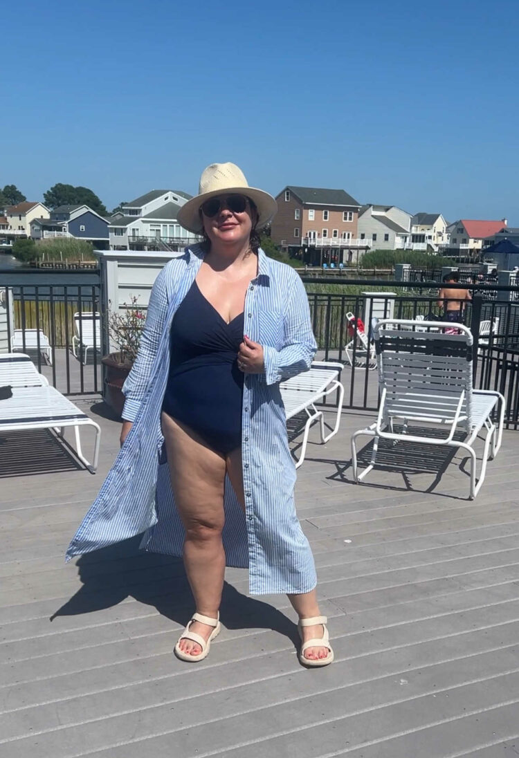 Alison wearing the Universal Standard Odeon shirtdress as a swim coverup over a navy swimsuit. She is wearing a Banana Republic Factory straw fedora.