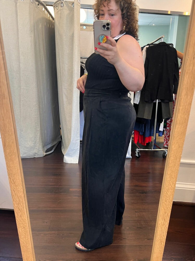 Alison of Wardrobe Oxygen trying on the Lee sleeveless sweater and Cooling Cupro wide leg pants in black at the Universal Standard trunk show in Washington DC