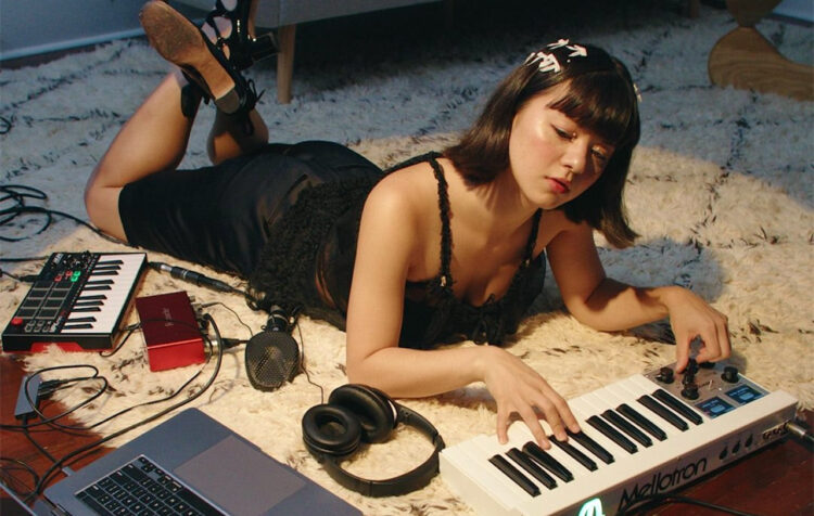 photo of mikayla geier lying on the floor playing a keyboard