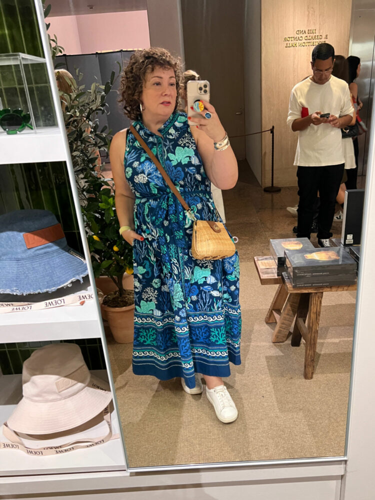 Alison of Wardrobe Oxygen in the Met gift shop taking a mirror selfie wearing a Printfresh blue sleeveless belted shirtdress that hits low calf