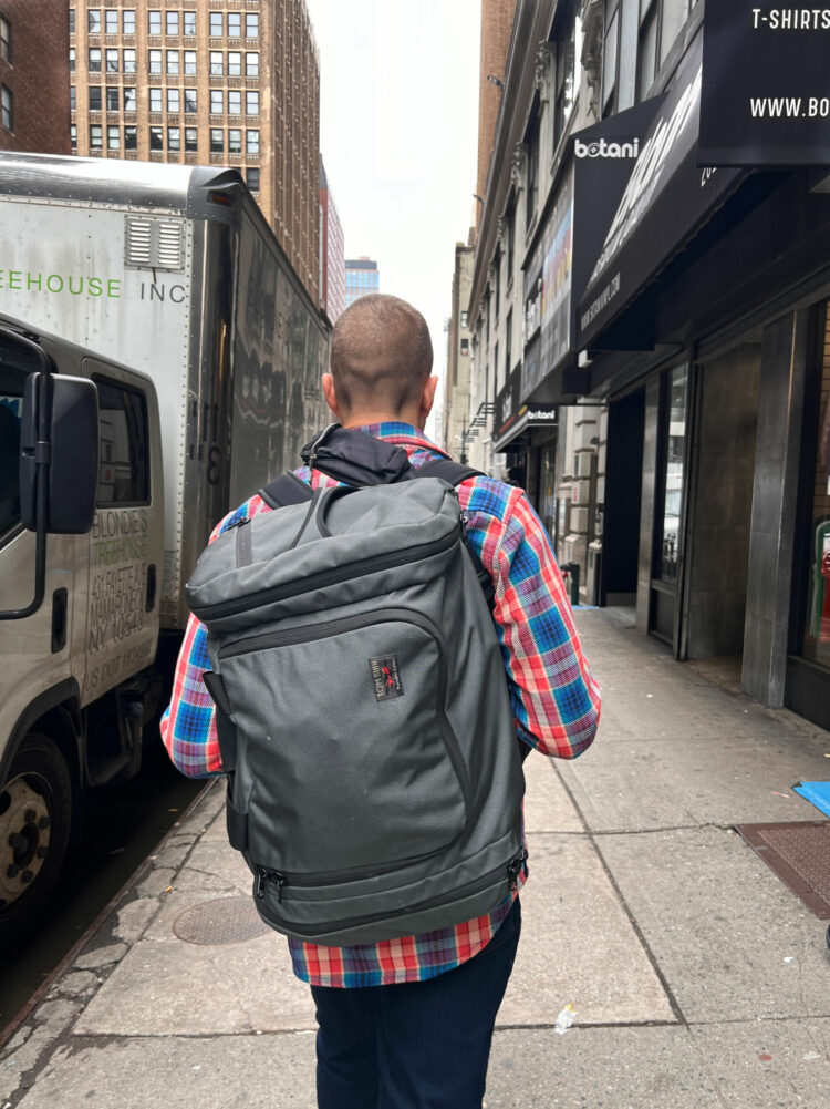 A man walking through the street of NYC wearing a Tom Bihn Aeronaut 45 as a backpack