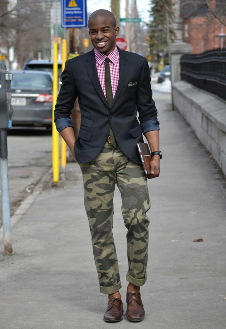 man in camo pants, brown dress shoes, a pink shirt, navy tailored blazer and tie.