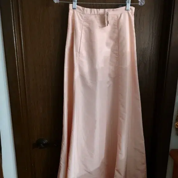 a blush pink taffeta ball skirt hanging on a hanger over a door