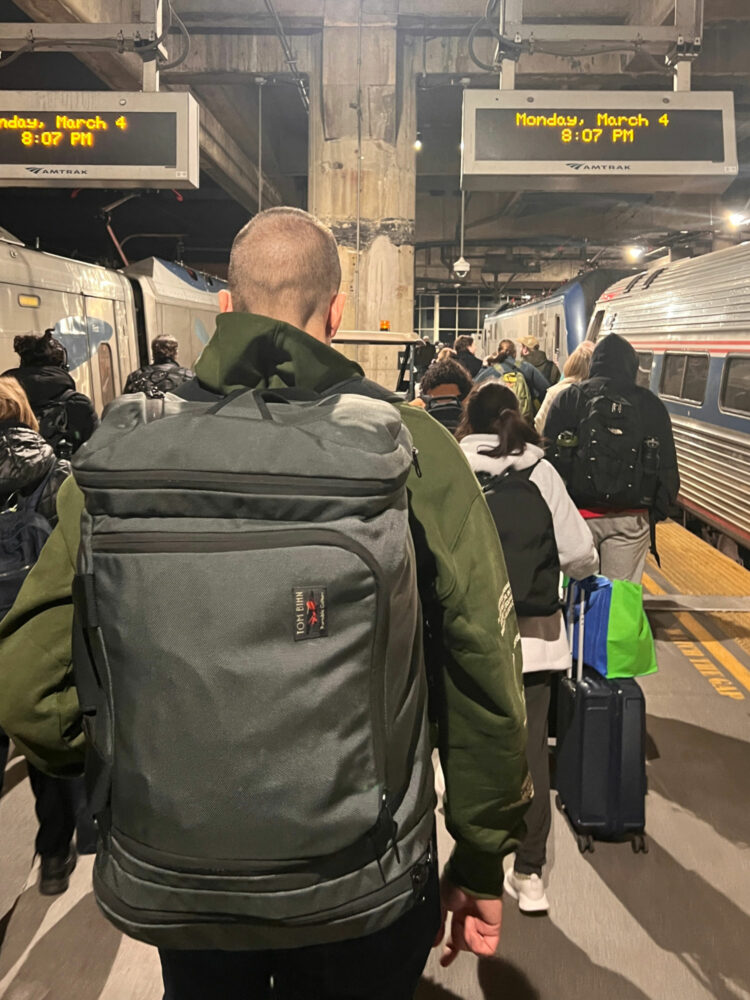 Man in a train station wearing the Tom Bihn Aeronaut 45 as a backpack