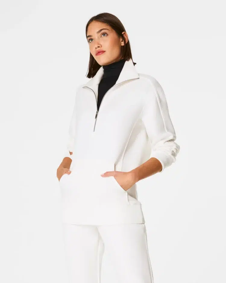 a model wearing Spanx AirEssentials zip tunic and pants in Powder white with a black fitted turtleneck