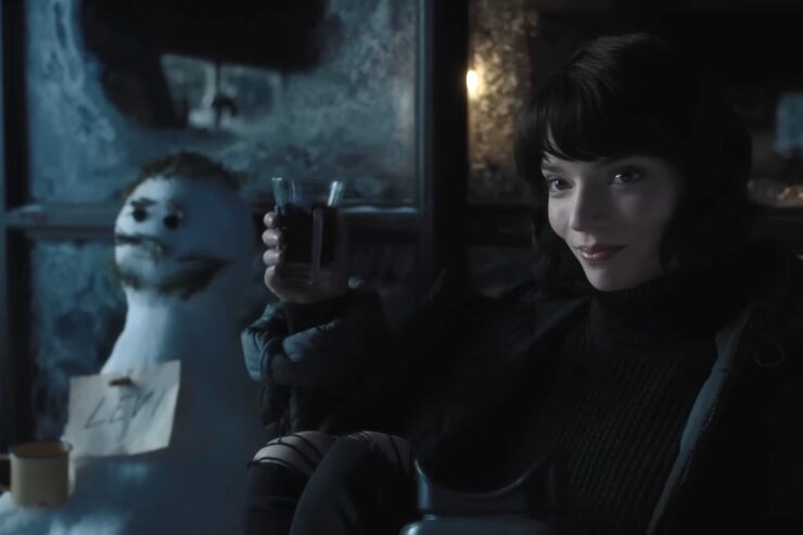 Anya Taylor-Joy in The Gorge, toasting a glass of vodka while sitting next to a snowman